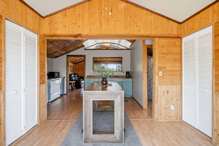 Wood-paneled interior with vaulted ceilings, louvered bi-fold doors, and a wood-finish flooring