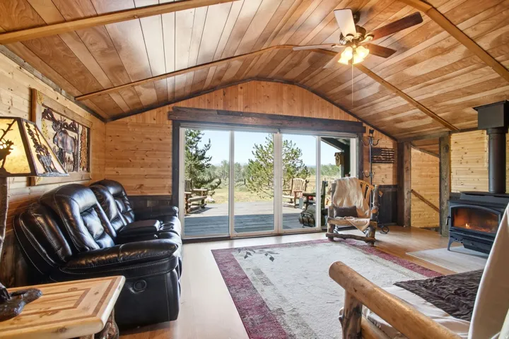 Wood-paneled vaulted ceiling with exposed beams, wood-finish flooring, and a ceiling fan