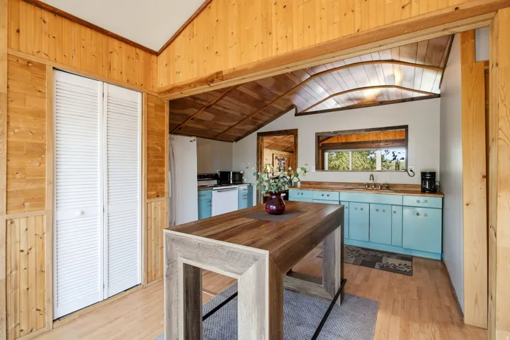 Wood-finish paneling and wainscoting, vaulted wood-finish ceiling, wood-finish flooring, and light blue cabinetry