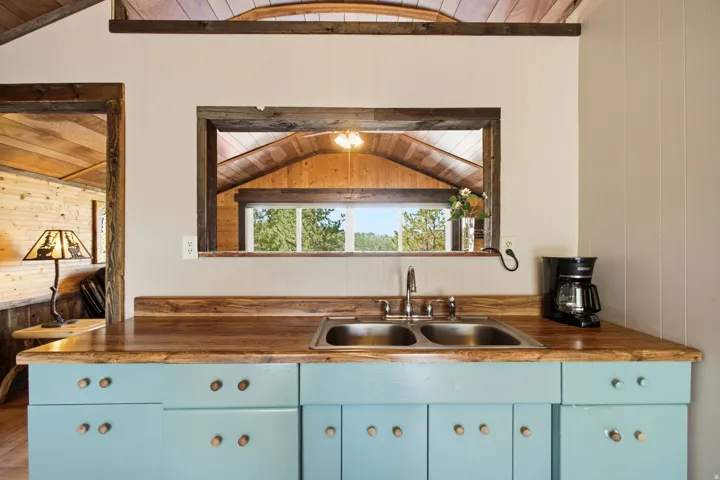 Wood-finish countertops, dual stainless steel sinks, and light blue cabinetry