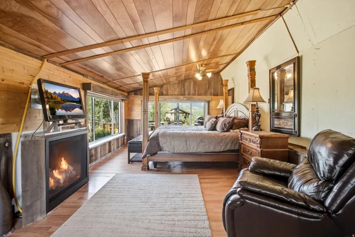 Wood-paneled vaulted ceiling with exposed beams, wood-finish flooring, built-in fireplace, and expansive windows