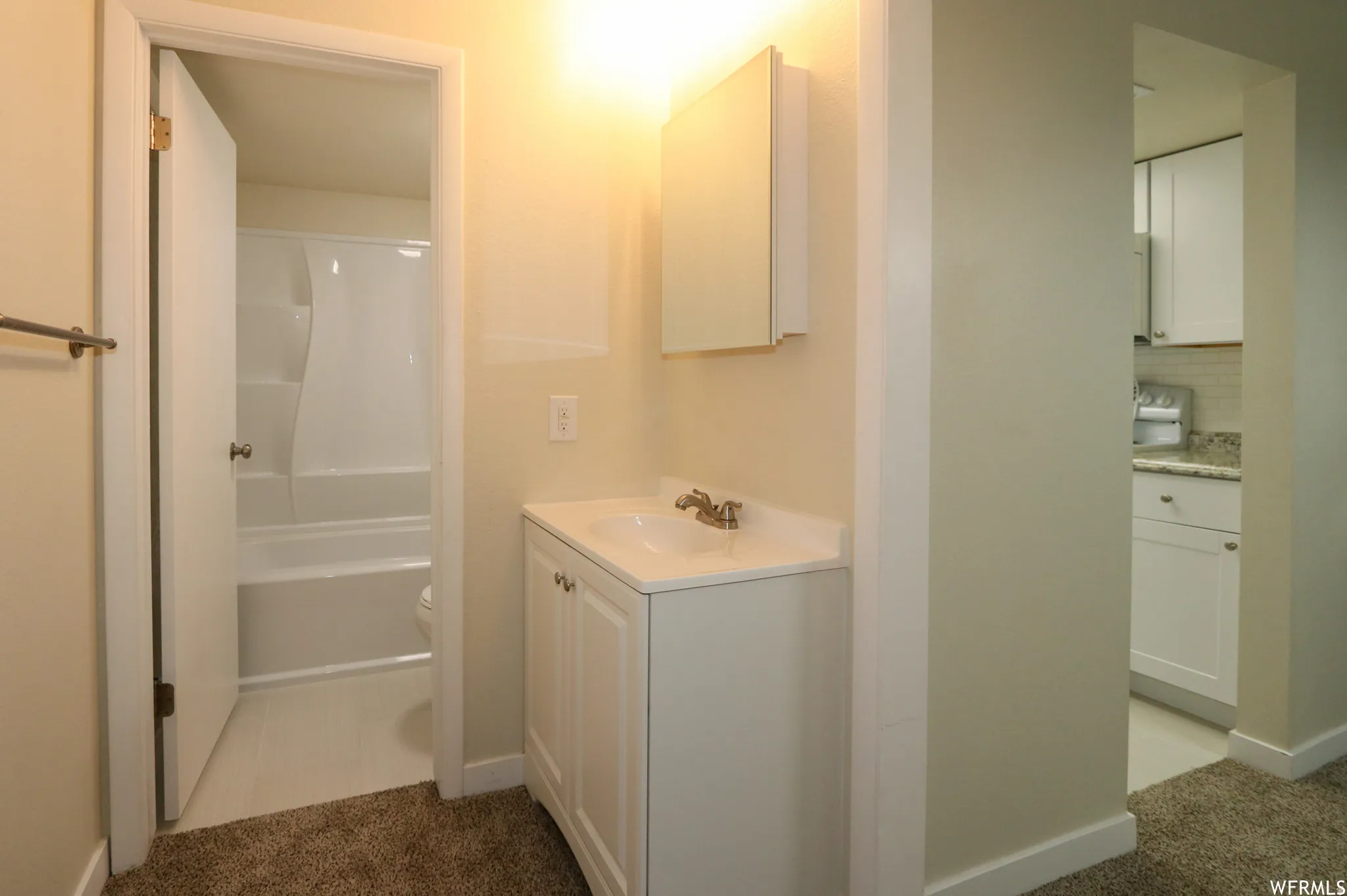 White vanity with integrated sink, medicine cabinet, and overhead light fixture