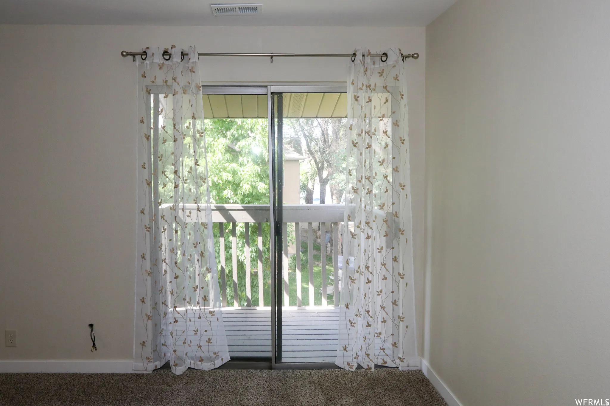Sliding glass door leading to a private balcony with wood railing
