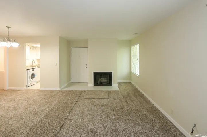 Carpeted living area featuring a fireplace, a window with blinds, and a ceiling-mounted light fixture