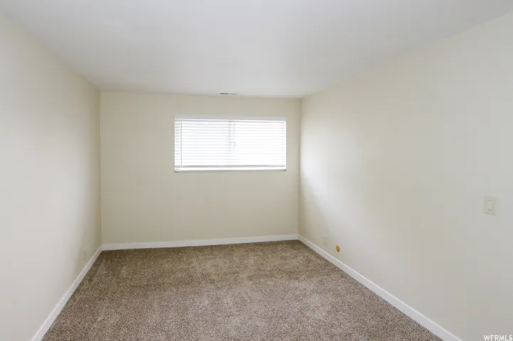 Neutral wall color, carpeted flooring, window with blinds