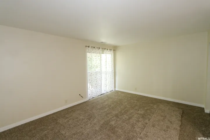 Sliding glass door, light-colored walls, and carpet flooring