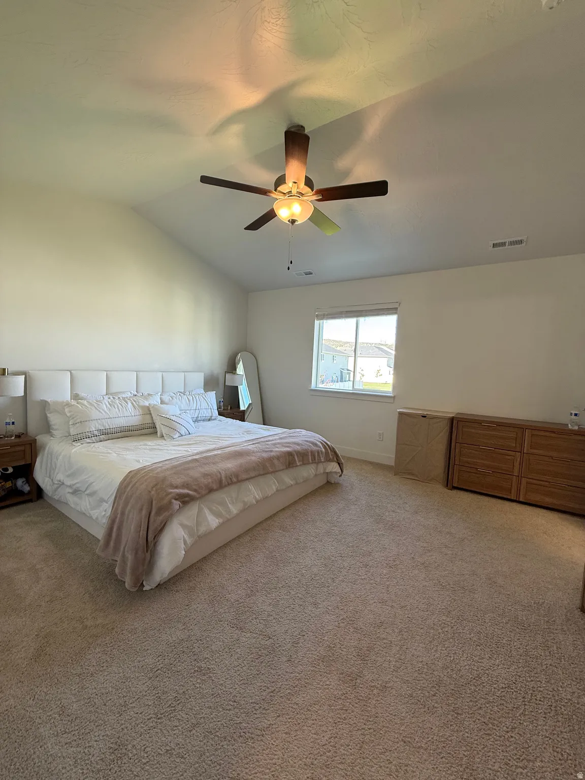 Vaulted ceiling with a ceiling fan, carpet flooring, and a window with blinds