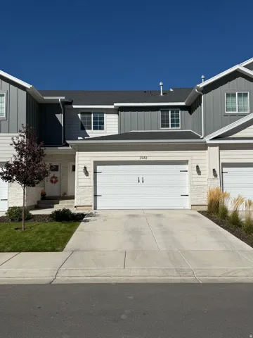 Two-story exterior with horizontal siding and vertical panel accents, attached garage, concrete driveway, and front lawn