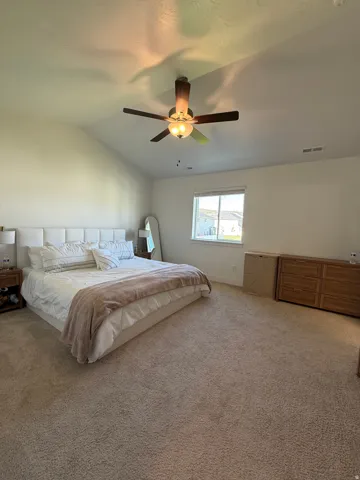 Vaulted ceiling with a ceiling fan, carpet flooring, and a window with blinds