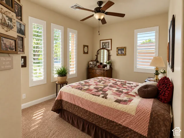 Carpeted bedroom with a ceiling fan light fixture