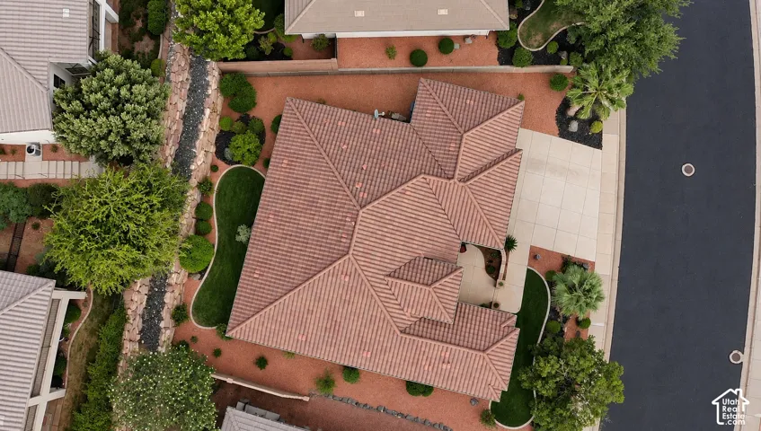 Terracotta tile roofing with multiple gables, extensive gravel landscaping, established trees and shrubs, paved driveway, and manicured lawn areas