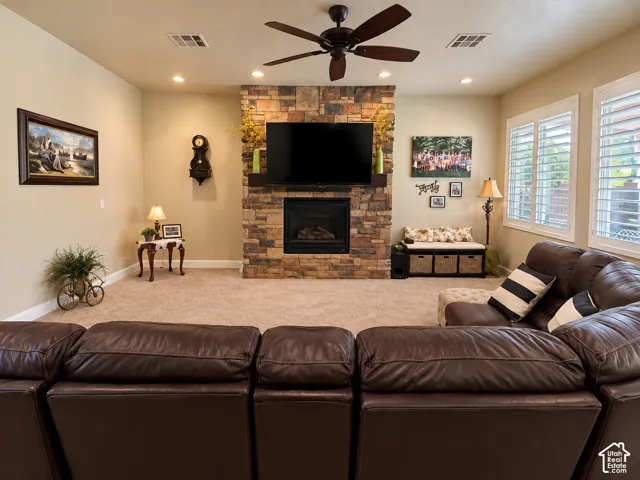 Stone-faced fireplace with a mantel, recessed lighting, ceiling fan, and plantation shutters