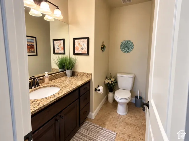 Half bath located across the hall from the den/bedroom, vanity with a granite countertop, built-in oval sink, and dark wood-finish cabinetry