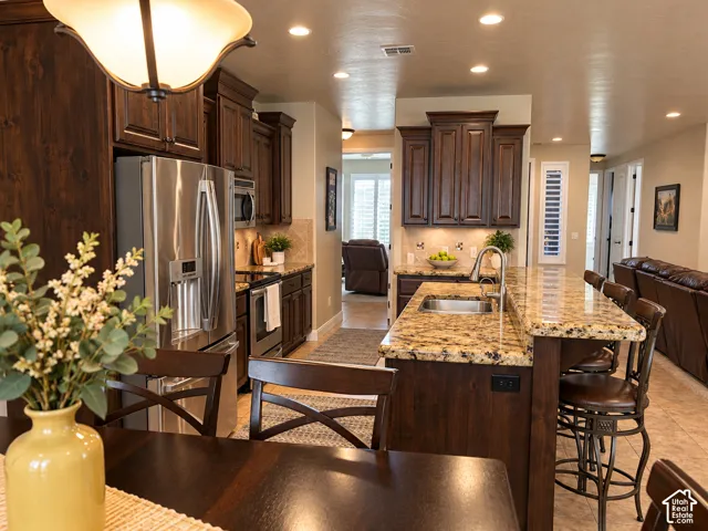 Kitchen featuring dark wood cabinetry, stainless steel appliances, granite countertops, and recessed lighting