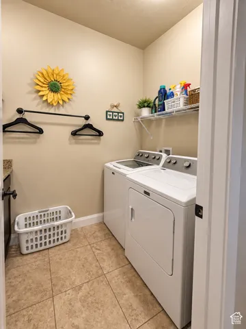 Laundry area featuring tile flooring, white appliances, built-in shelving, and a wall-mounted hanging rod