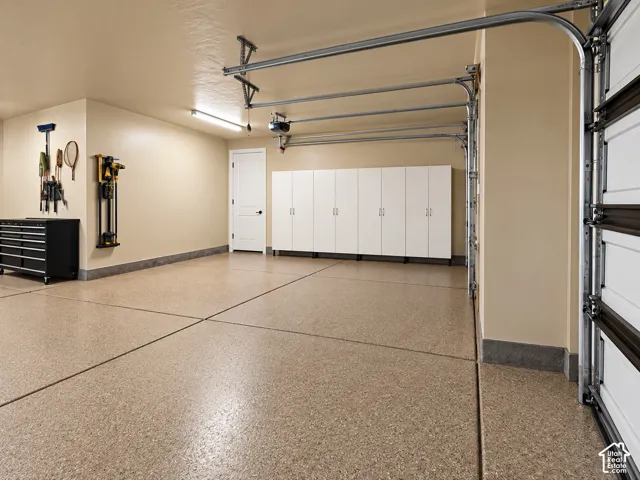 Expansive garage featuring a speckled epoxy floor, extensive white built-in cabinetry, and a paneled entry door