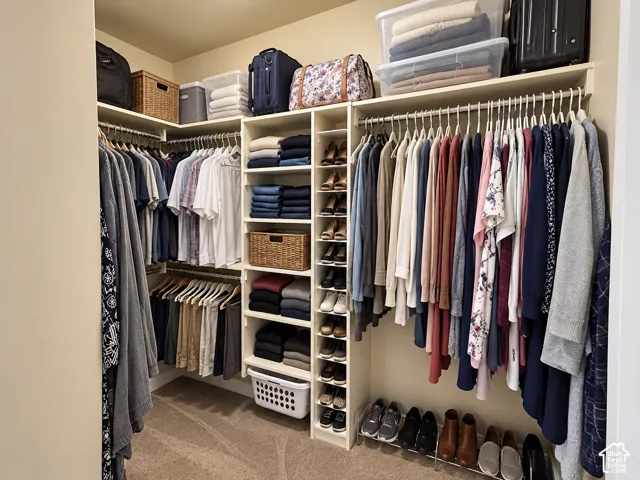 Primary closet. Custom closet system featuring extensive shelving, multiple hanging rods, built-in shoe storage, and overhead storage options