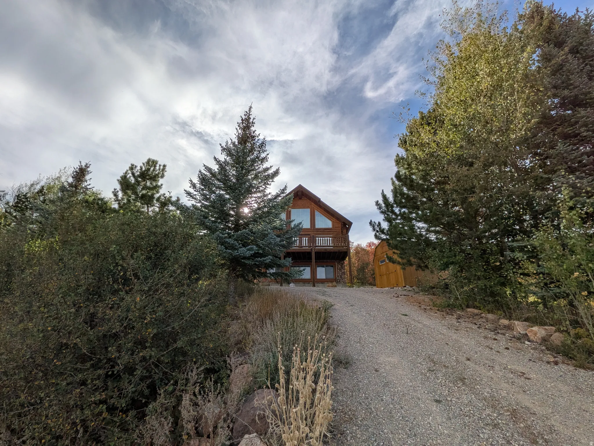 Wood-clad exterior with A-frame architectural style, featuring an upper-level balcony and expansive windows