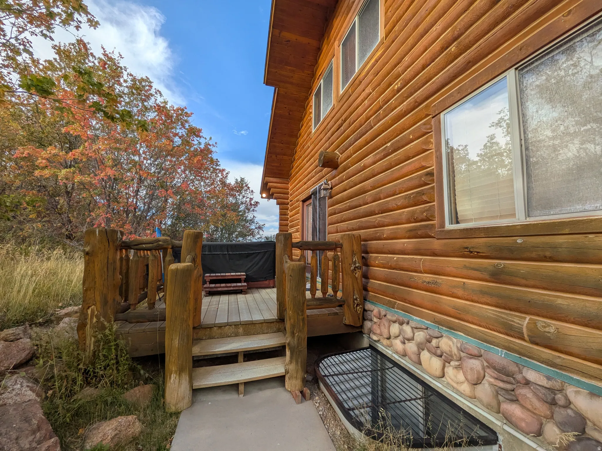 Deck off of the Master Bedroom with Spa and wildlife views. Wood-sided exterior featuring multiple windows, a wood deck with rustic wood railings, and a stone-clad foundation
