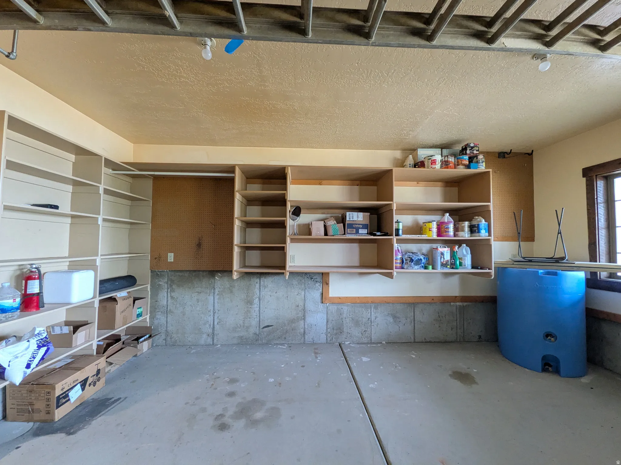 Concrete flooring, built-in shelving, concrete foundation walls, exposed ceiling joists
