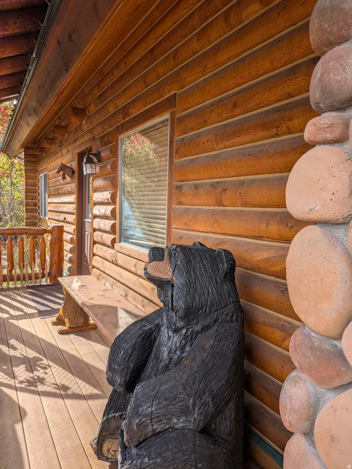Log cabin exterior featuring wood siding, stone accents, and a wood-plank deck