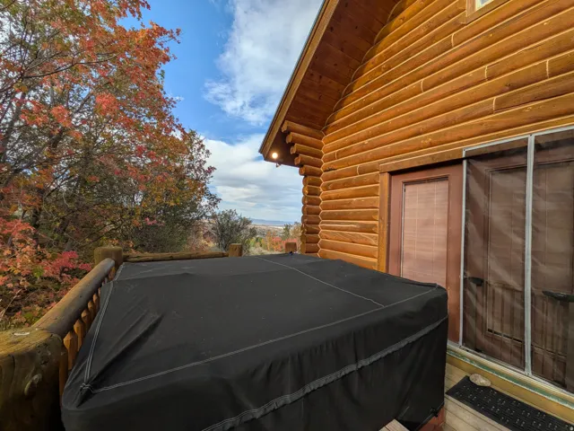 Deck off of the Mater Bedroom with natural wood siding, wood railing, and a covered outdoor spa