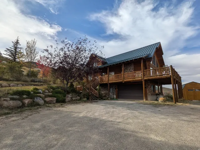 Log home exterior featuring a stone foundation, wood log siding, and a metal roof