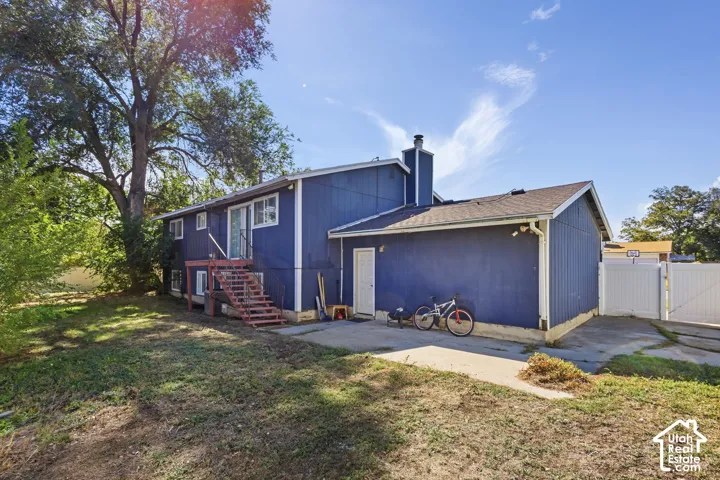 Two-story exterior with blue siding, a multi-level deck, concrete patio, and a white fence