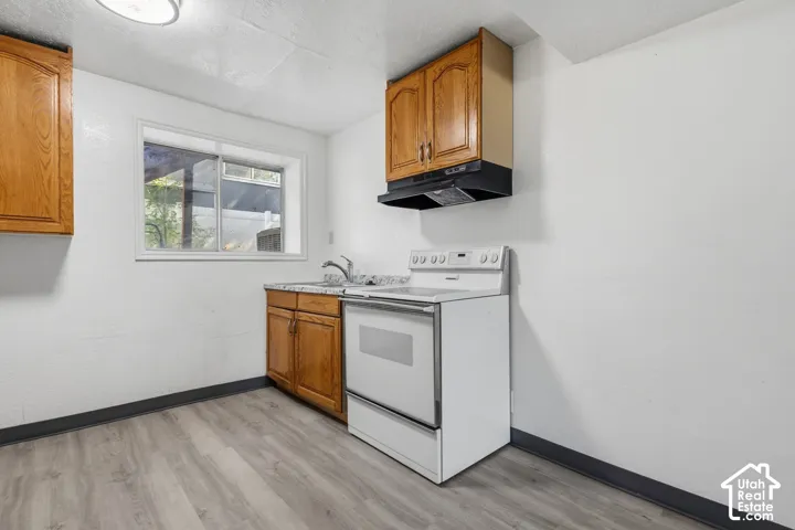 Kitchen featuring wood-finish cabinetry, white appliances, and wood-finish flooring