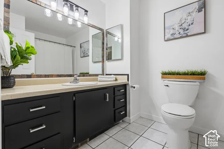 Vanity with a single basin sink, matte black cabinetry, and a large mirror with a tiled frame