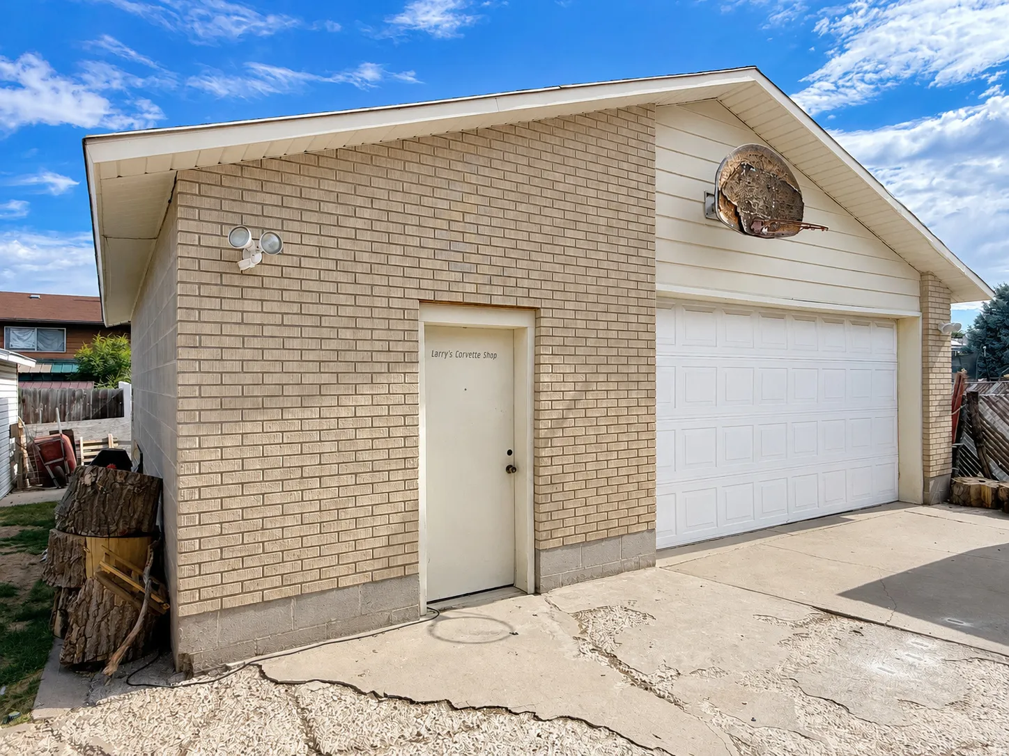 Brick exterior garage with a white panel garage door, a side entry door, and concrete driveway