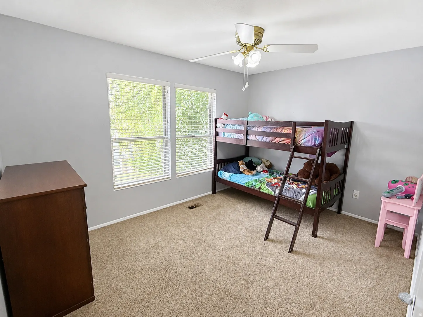 Two windows with horizontal blinds, neutral wall paint, and a ceiling fan with light fixture