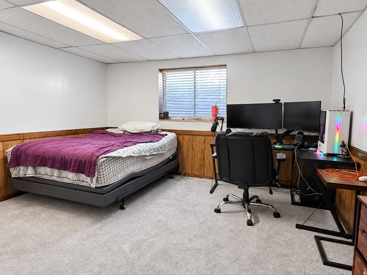 Wall-to-wall carpeting, wood-paneled wainscoting, and a drop ceiling with integrated lighting