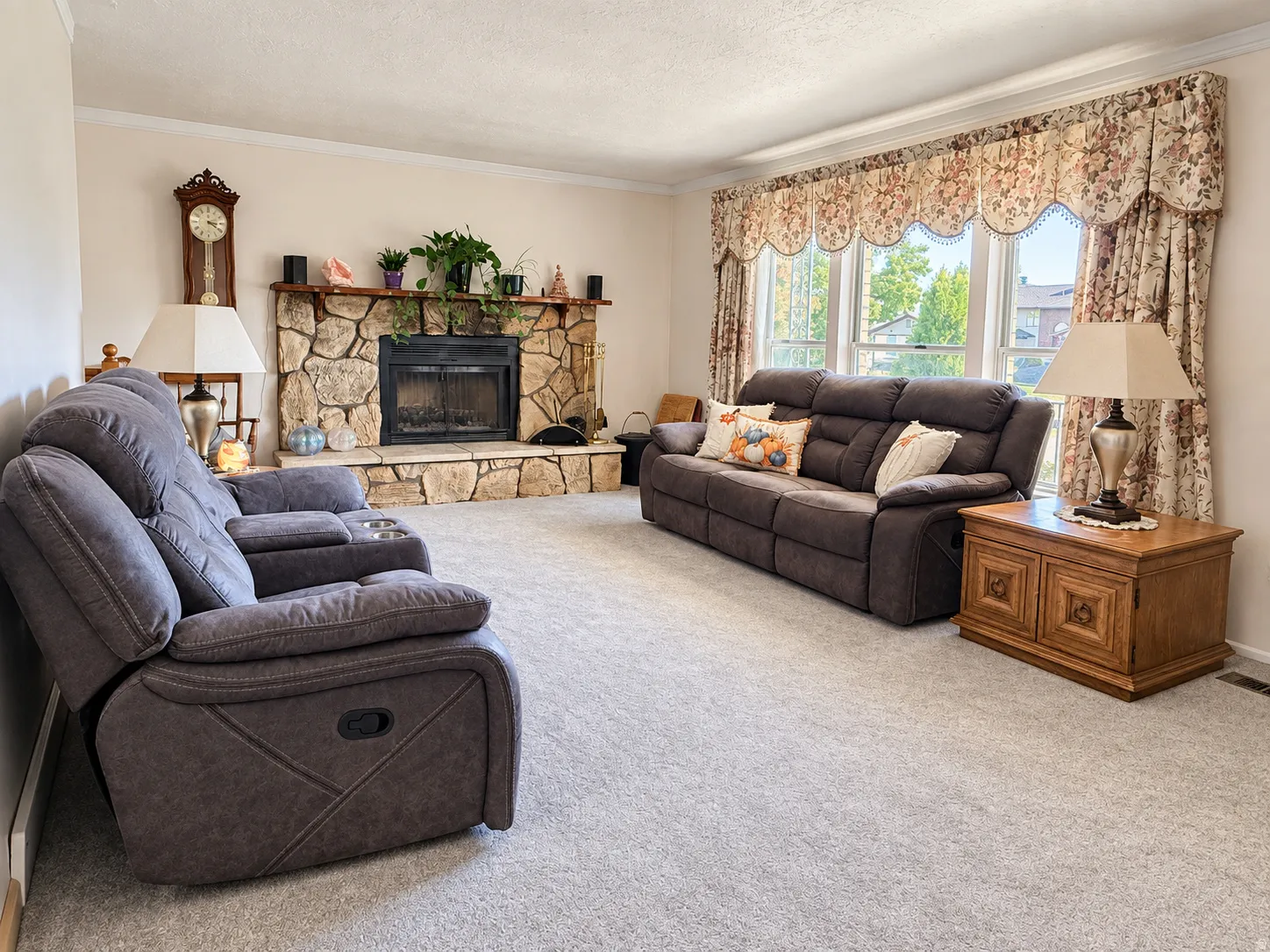 Spacious living room anchored by a stone fireplace with built-in shelving and mantelpiece, paired with comfortable seating arrangements