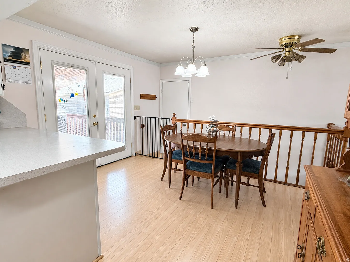 Wood-finish flooring, half-wall with wood railing, ceiling fan, pendant light fixture, and French doors to exterior