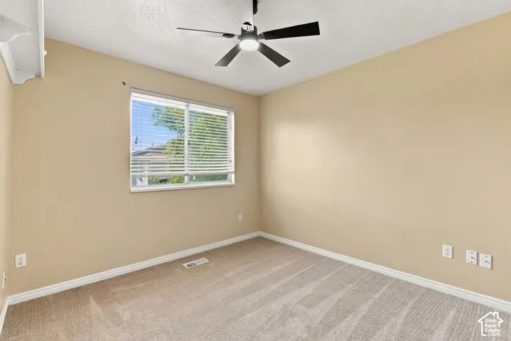 Recessed window with blinds, overhead ceiling fan, and neutral carpet flooring