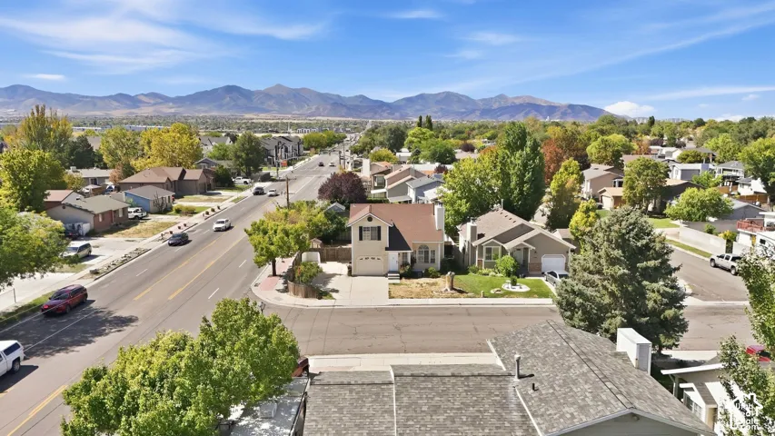 Residential neighborhood with mature trees, mountain backdrop, and paved roadways