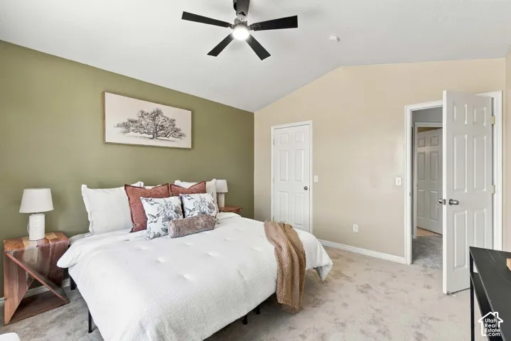 Vaulted ceiling with a black ceiling fan, light gray carpeting, and white paneled doors