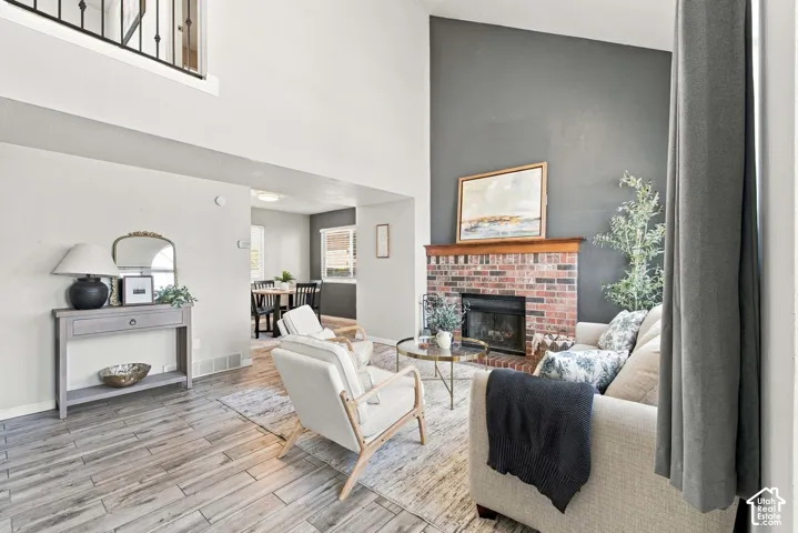 Soaring vaulted ceilings, brick fireplace with wood mantel, wood-finish flooring, and an open-concept layout