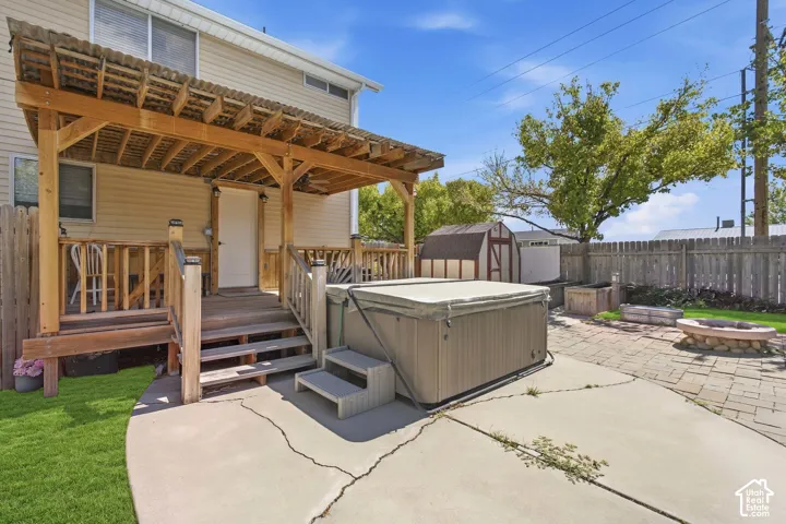 Expansive concrete patio area, hot tub, wood privacy fence, and storage shed