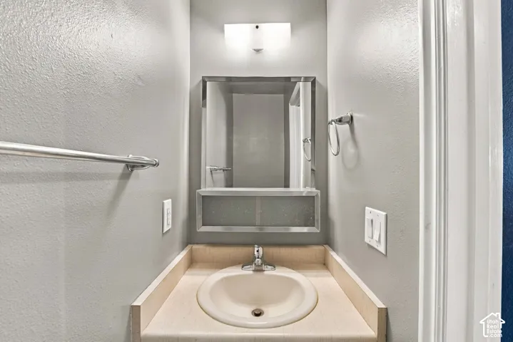 Recessed vanity with an integrated sink, laminate countertop, and overhead wall-mounted lighting