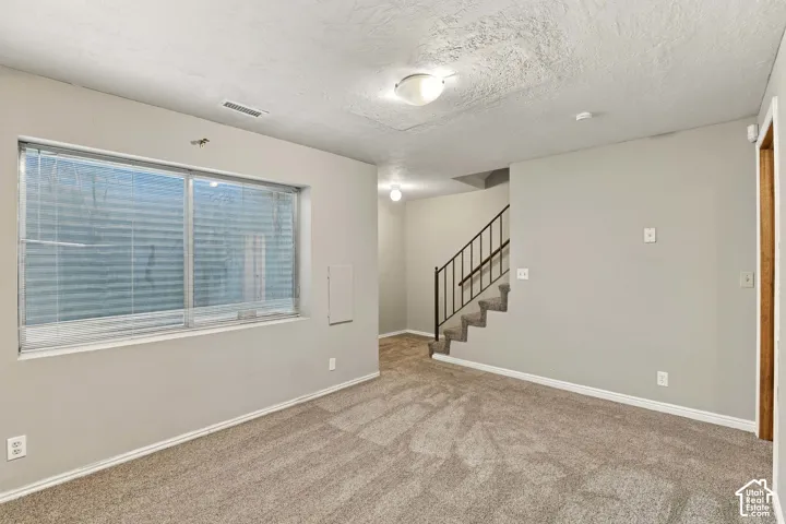 Carpeted flooring, recessed window, flush-mount lighting, and a staircase with metal railings