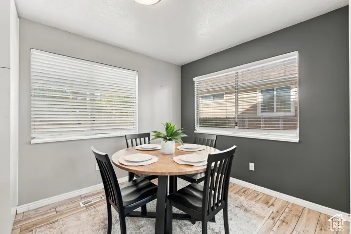 Recessed ceiling lighting, wood-finish flooring, two windows with blinds, and contrasting accent wall