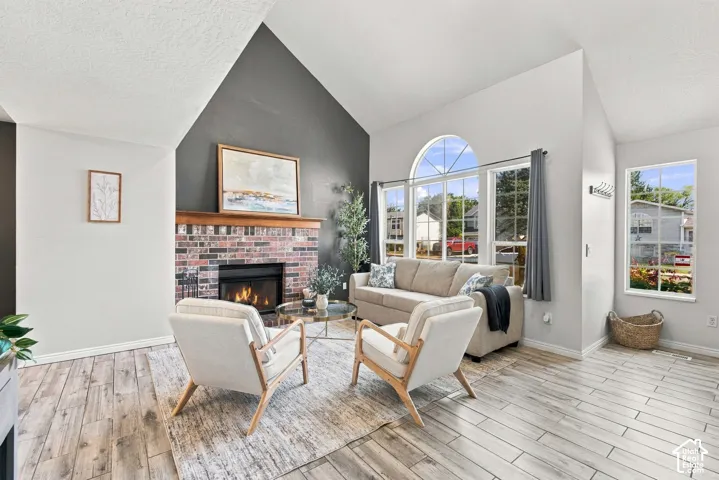 Vaulted ceilings, a brick-surround fireplace with a wood mantel, and expansive windows including an arched transom