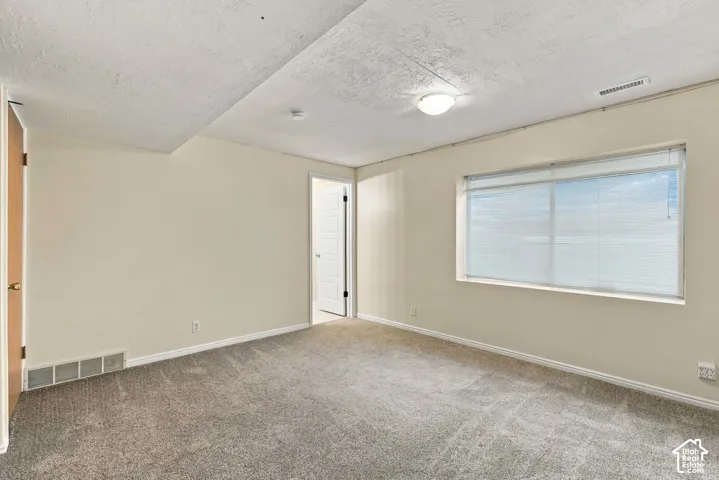 Wall-to-wall carpeting with a neutral finish, light-toned wall paint, and a window with blinds