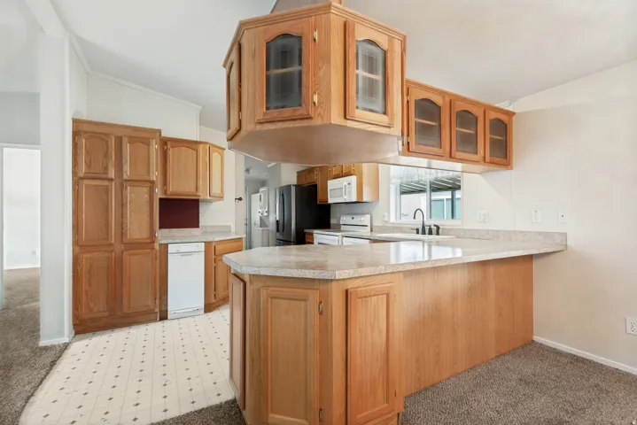 Kitchen featuring wood cabinetry, stone-finish countertops, an integrated kitchen island, and a built-in dishwasher
