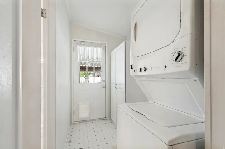 Laundry area with a stackable washer and dryer, patterned flooring, and a rear entry door with a window