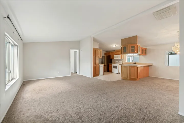 Open-concept living area featuring a kitchen with wood cabinetry, a breakfast bar, and integrated appliances