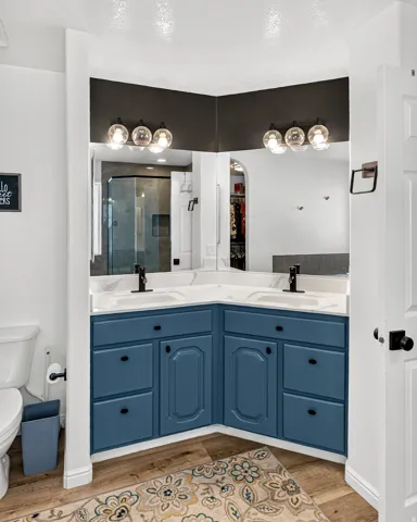 Corner dual vanity with blue cabinetry, white countertops, and black fixtures
