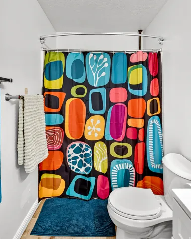 White toilet with a built-in toilet paper holder and a curved shower rod